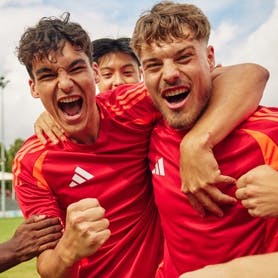 A group of soccer players cheering and wearing adidas team gear