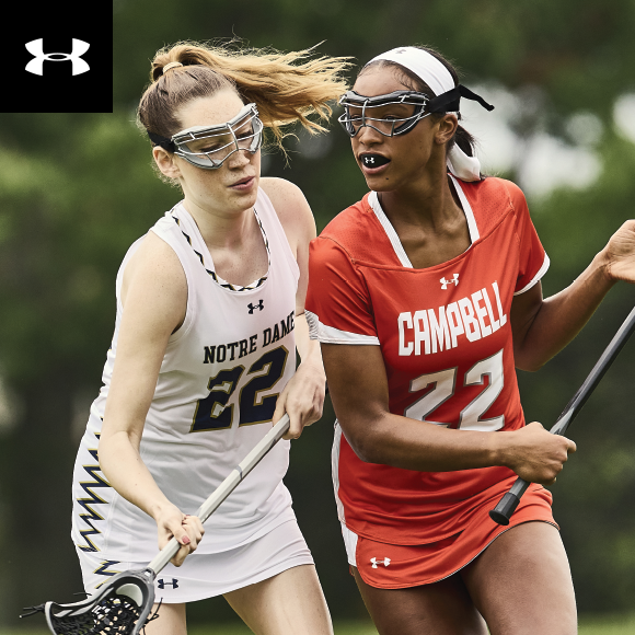 Two female lacrosse players playing lacrosse  wearing Under Armour uniforms