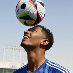A soccer player balancing an adidas soccer ball on his head
